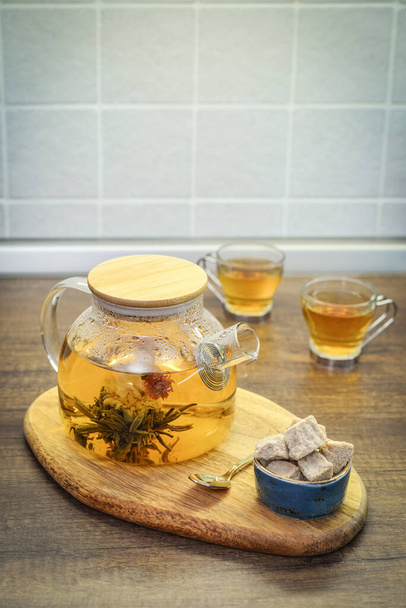 Blooming flowering tea in glass teapot and two cups on kitchen worktop closeu - Fotografie, Obrázek