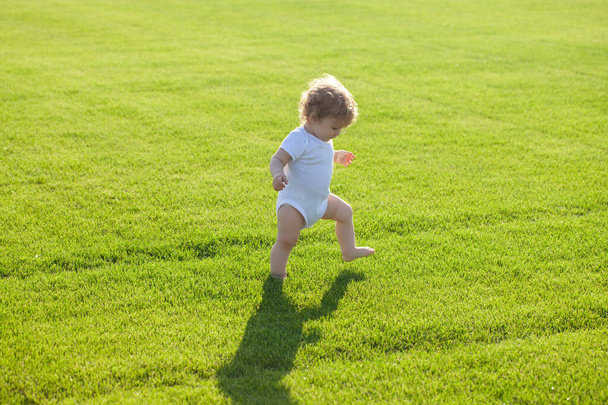 First step. Baby bare legs standing on green grass. Healthy child. - Photo, image