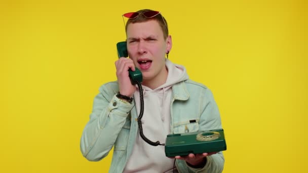 Verrückter, aufrichtiger Teenie-Mann, der auf einem kabelgebundenen Oldtimer-Telefon der 80er Jahre spricht, alberne, lustige Gesichter macht - Filmmaterial, Video