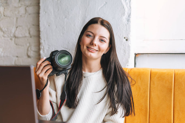 Брюнет посміхається молодій жінці-фотографу, що працює зі своєю камерою та ноутбуком у кафе. - Фото, зображення