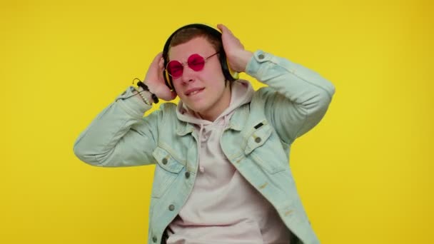 Alegre hombre atractivo escuchando música a través de auriculares y bailando disco tonteando alrededor de divertirse - Metraje, vídeo