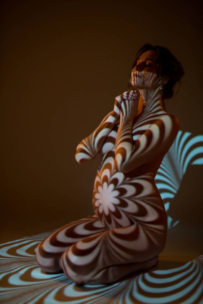 Nude pregnant woman in dark with ornamental shadows on body - Fotografie, Obrázek