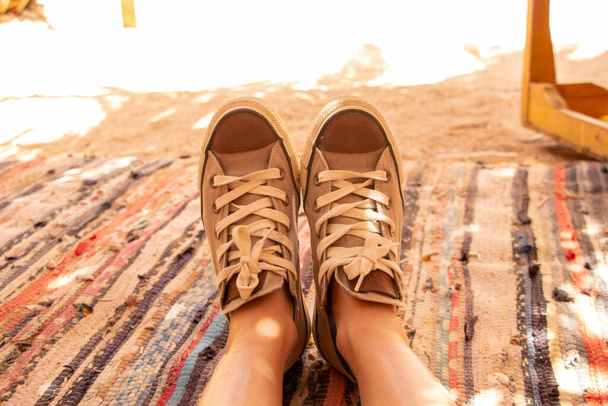 gambe femminili in tessuto leggero sneakers su un tappeto multicolore nel deserto in tende di boudoins primo piano - Foto, immagini