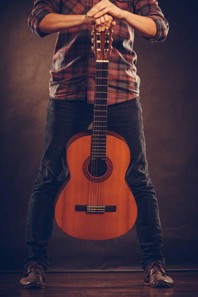 Music, hobby concept. Artist is standing with wooden guitar. Man is  holding the instrument.  - Foto, immagini