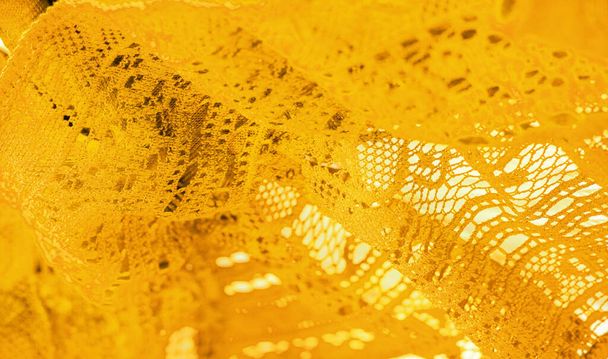 Желтые кружева ткани, тонкая открытая ткань, как правило, из хлопка или шелка, сделанные с помощью петель, скручивание или вязание нитей в узоры. Фоновая текстура, рисунок. - Фото, изображение