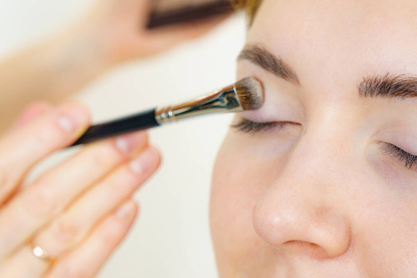 Face painting. Makeup artist applying shadows to model eye. Cosmetic beauty procedures, make up stage. - Φωτογραφία, εικόνα