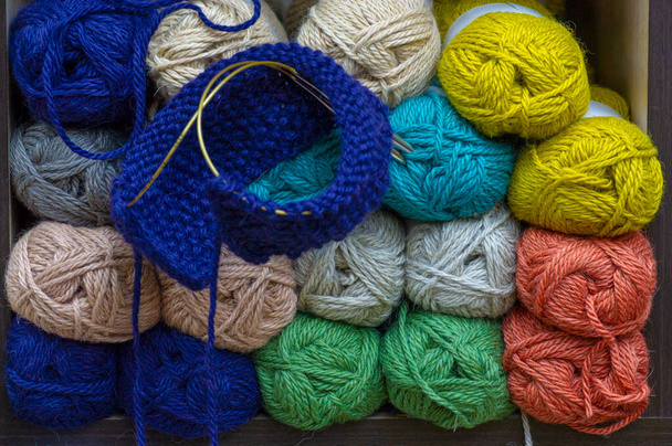 голубая пряжа и вязание. на фоне пряжи с шерстяной нитью разных цветов - Фото, изображение
