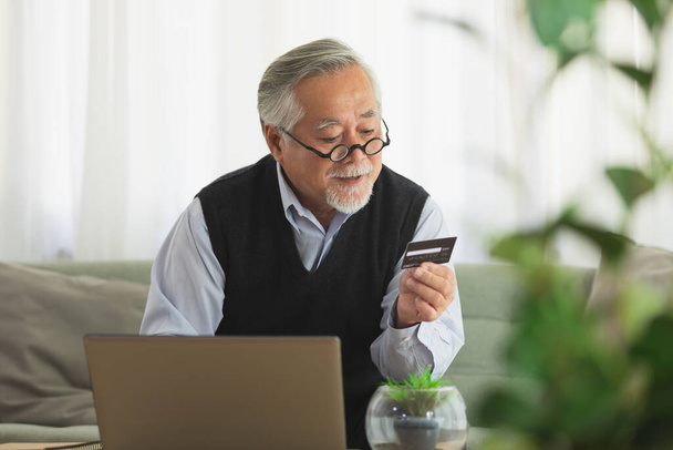 Asiatischer älterer Mann benutzt Kreditkarte beim Online-Einkauf - Foto, Bild