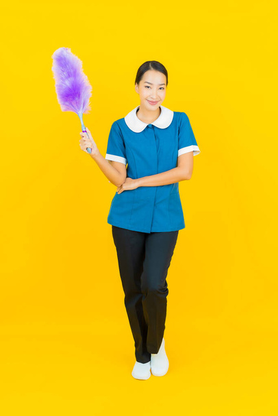 Portrait beautiful young asian woman maid and housekeeping smile with action on yellow color background - Fotoğraf, Görsel