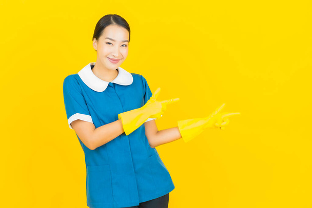 Retrato bonito jovem asiático mulher empregada doméstica e sorriso com ação no fundo de cor amarela - Foto, Imagem