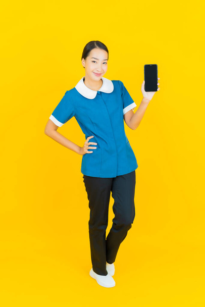 Portrait beautiful young asian woman maid and housekeeping smile with action on yellow color background - Photo, image