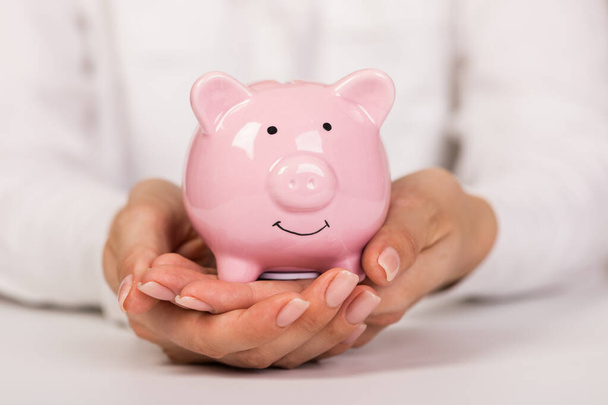 Piggy bank in hands on light background, space for text. Finance, saving money - Fotografie, Obrázek