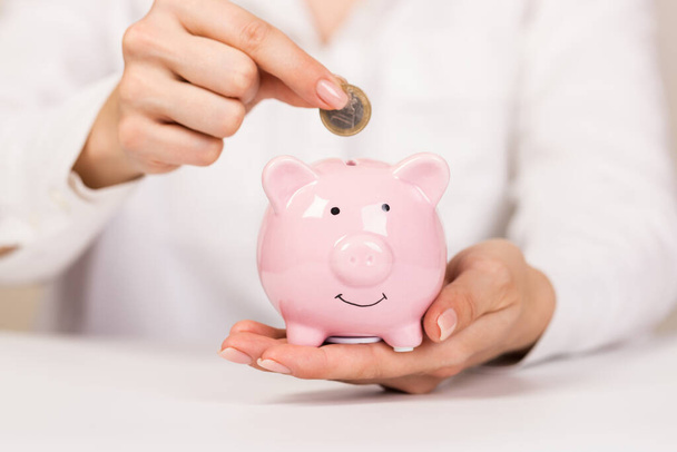 piggy Bank on a light background and human hand putting coin in piggy bank. copyspace for design. - Fotoğraf, Görsel