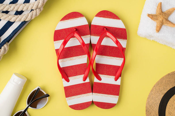 Top view photo of beach bag towel starfish hat cream bottle sunglasses striped red and white flip-flops on isolated pastel yellow background, - Fotó, kép