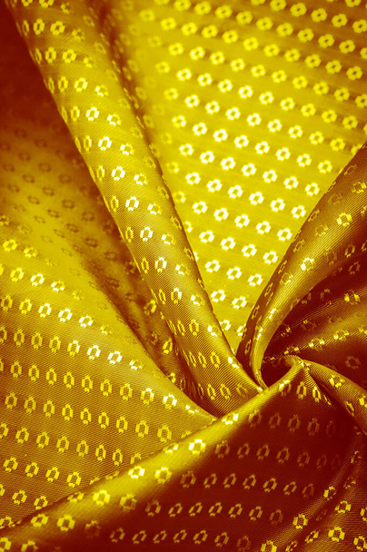 Tejido de seda hecho de oro amarillo, con pequeños patrones de cuadrados, rombos. Riqueza y lujo en su diseño. Textura de fondo, ornamento decorativo - Foto, imagen