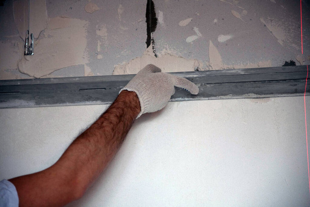 строитель оштукатуривает фасад высотного здания шпаклевочным ножом - Фото, изображение