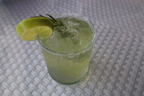 A closeup of a margarita with salt rim, lime, and rosemary garnish - Foto, Imagen