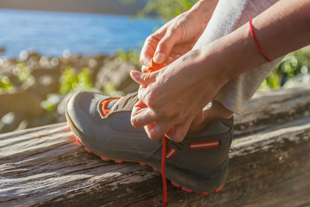 A woman tying her orange shoelaces in the park, getting ready to jog - Фото, зображення