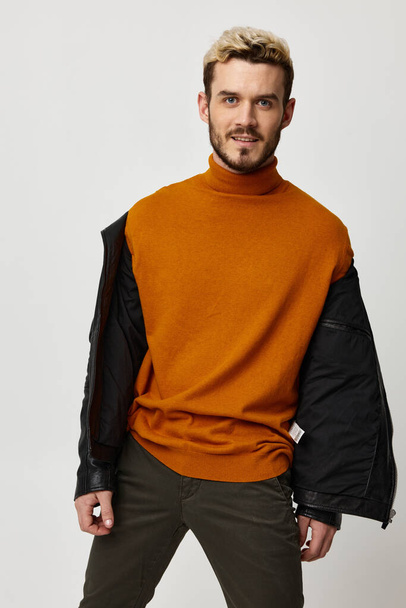 coche de moda con una chaqueta desabotonada y un suéter naranja se ríe sobre un fondo claro - Foto, imagen