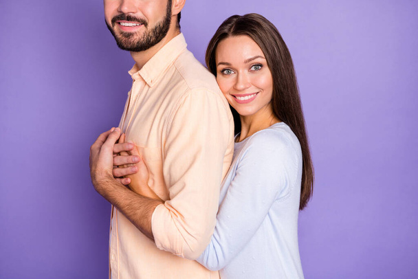 Profile side photo of positive young spouses woman hold hands man chest back hug isolated on violet color background - Fotografie, Obrázek