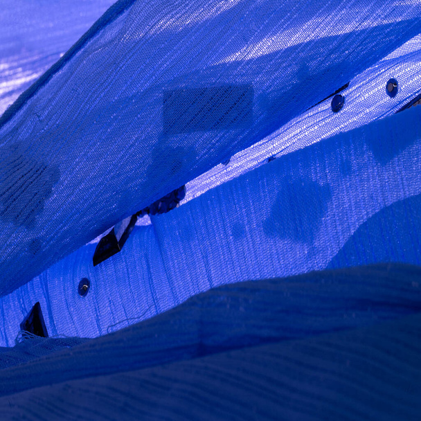 Patrón de seda, tela azul con piedras facetadas decorativas pegadas. fondo de textura con piedras de colores brillantes, diseño de fondo de textura - Foto, Imagen