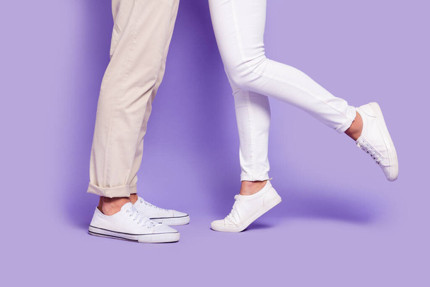 Cropped profile side photo of couple legs wear pants white shoes date day together isolated on purple color background - 写真・画像