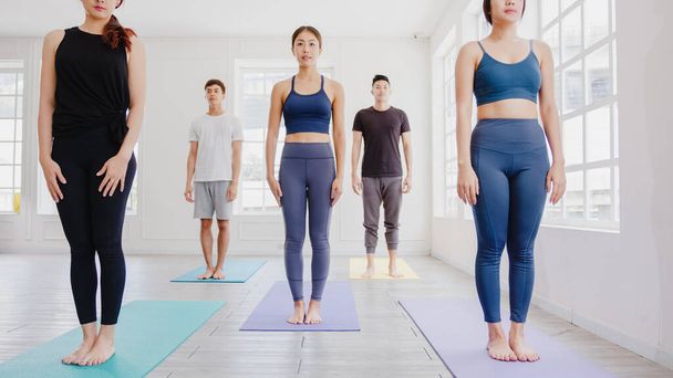 Young Asian sporty attractive people practicing yoga lesson with instructor. Asia group of women exercising healthy lifestyle in fitness studio. Sport activity, gymnastics or ballet dancing class. - 写真・画像