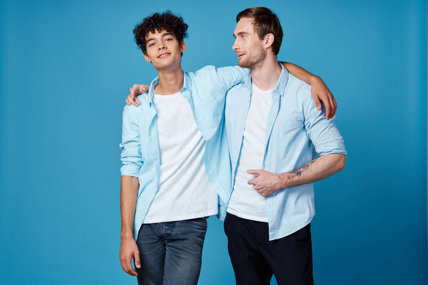 Junge Männer in blauen Hemden umarmen sich an isolierten Hintergründen Freunde Spaß - Foto, Bild