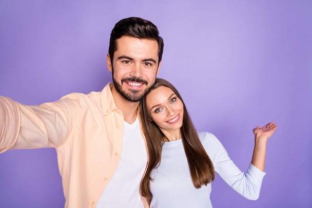Photo of brown haired trendy stylish couple make selfie show empty space ad isolated on purple color background - 写真・画像