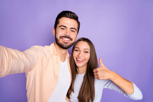 Photo of brunette trendy stylish couple make thumb up take selfie camera charming smile isolated on violet color background - Fotoğraf, Görsel