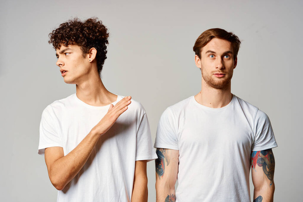 dos hombres con camisetas blancas están de pie junto a las emociones de amistad - Foto, Imagen
