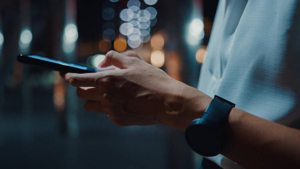 Nuori Aasian liikenainen muoti toimistovaatteita älypuhelimella kirjoittamalla tekstiviestin samalla seistä ulkona kaupunkien moderni kaupunki yöllä. Liiketoiminta liikkeellä konsepti. lähikuva laukaus. - Valokuva, kuva