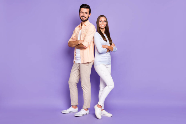 Full size portrait of two cheerful persons standing back to back folded arms isolated on purple color background - Foto, afbeelding