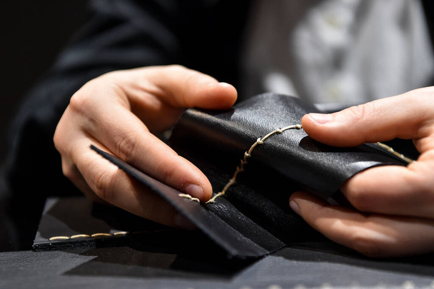 A leather craftsman works with leather. Sews leather goods. Use needle and thread for sewing.  Making things handmade - 写真・画像