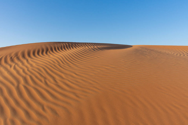 Sonnenuntergang in der Wüste über kreisförmig strukturierte und gemusterte Bergrücken, die spektakuläre, wechselnde Formen annehmen. Vereinigte Arabische Emirate oder Wüstenkonzept Sahara. - Foto, Bild