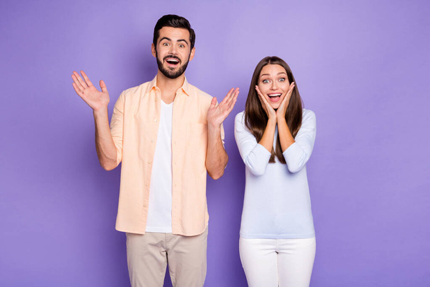 Photo of amazed man and woman couple raise hands hold cheekbones lucky discount isolated on violet color background - Fotoğraf, Görsel