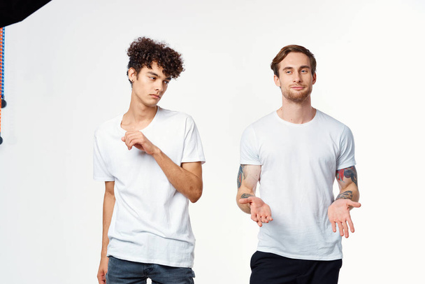 two men in white t-shirts stand side by side cropped view studio  - Foto, Imagen