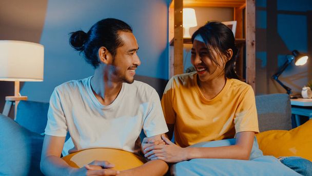 Gelukkig jong aziatisch paar man en vrouw kijken naar camera glimlach en vrolijk op video oproep online 's nachts in de woonkamer thuis, Blijf thuis quarantaine, getrouwd leven, Sociale afstandelijke concept. - Foto, afbeelding