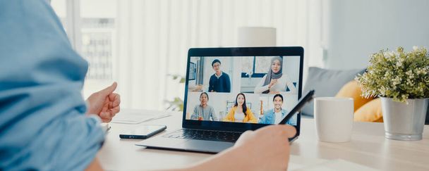 Young Asia businessman using laptop talk to colleagues about plan in video call meeting work from home at living room. Self-isolation, social distance, panoramic banner background with copy space. - Photo, image