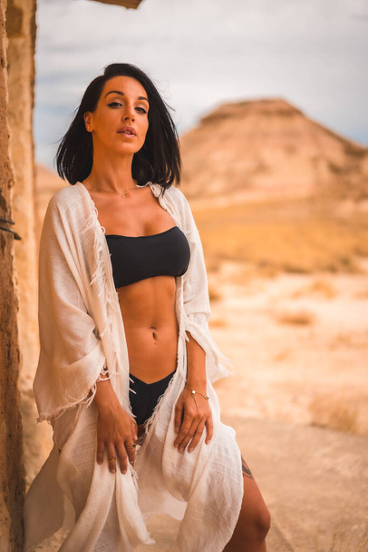 Lifestyle of a young brunette Caucasian girl in a white dress in a perched in a house in the desert - Foto, Bild