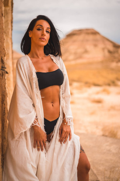 Lifestyle of a young brunette Caucasian girl in a white dress in a perched in a house in the desert - Foto, Bild