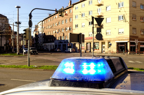 Blauwe zwaailichten op een politieauto in een stad in Duitsland. Huizen, auto 's en straten op de achtergrond. De focus ligt op de blauwe lichten. - Foto, afbeelding