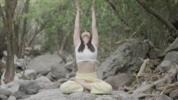 Chica haciendo pose de yoga al aire libre.Hermosa mujer sana respirando suavemente y se sienta en pose de loto. Relaja cuerpo y mente en la naturaleza al aire libre. Meditar y practicar yoga. Calma mujer deportes pacíficos. - Metraje, vídeo