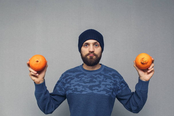 hombre barbudo muestra naranjas normales y feas, concepto de hemorroides o enfermedades proctológicas. - Foto, imagen