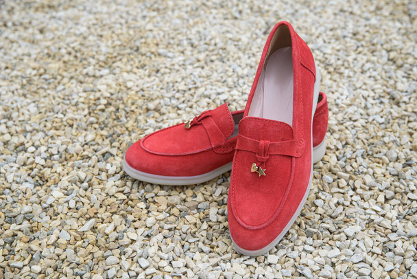 Zapatos mocasines de gamuza con estilo rojo para mujer en el fondo de piedra. Par de zapatos de mocasines femeninos de moda, al aire libre - Foto, imagen
