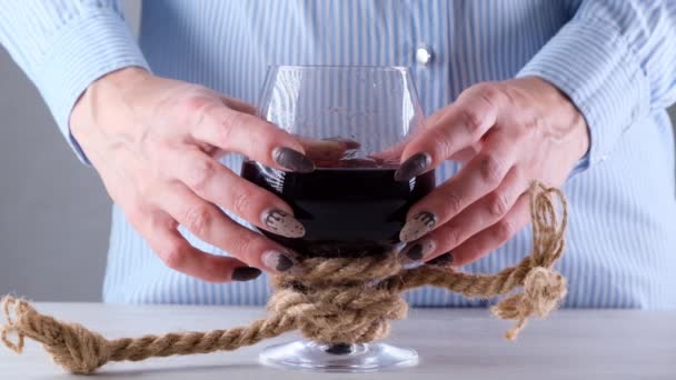 женские руки, держащие бокал вина, связаны джутовой веревкой. Концепция алкогольной зависимости. Проблема лечения алкоголизма - Кадры, видео