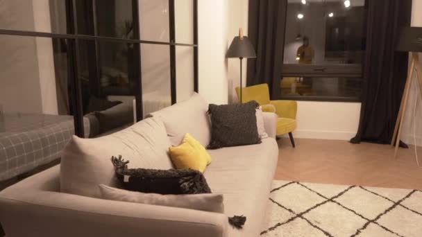Pan van links naar rechts schot van de moderne woonkamer interieur met comfortabele bank en design tapijt en gele kussens - Video