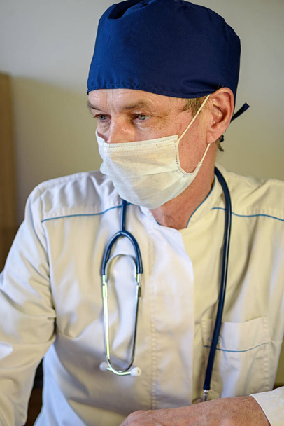 Doktor v bílém plášti naslouchá problémům pacienta doma. Koncept zdravotní péče pro seniory a nemocné - Fotografie, Obrázek