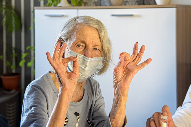 Médico atencioso e avó idosa positiva em máscaras em casa ou no hospital mostram OK. - Foto, Imagem
