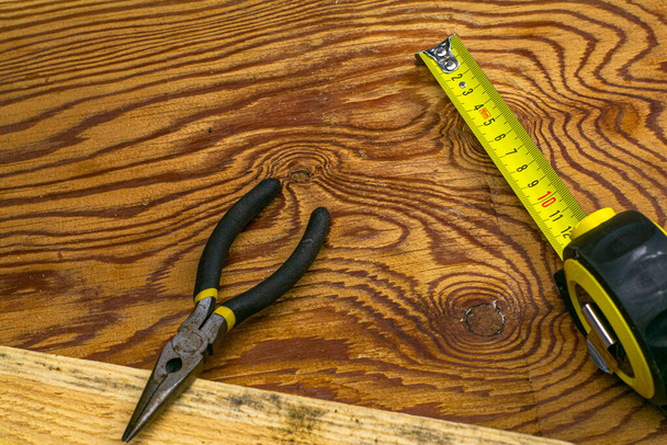 measuring tape measure board and pliers on the workbench. High quality photo - Photo, Image